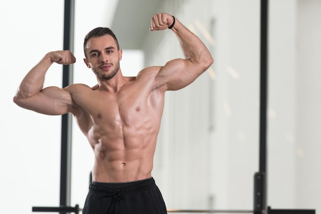 Hombre musculoso flexionando los músculos en el gimnasio