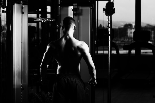 Hombre musculoso flexionando los músculos en el gimnasio