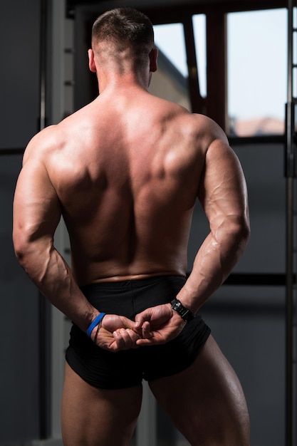 Hombre musculoso flexionando los músculos en el gimnasio