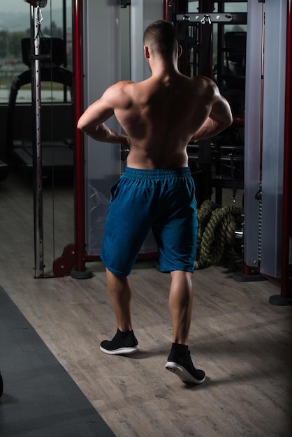 Hombre musculoso flexionando los músculos en el gimnasio