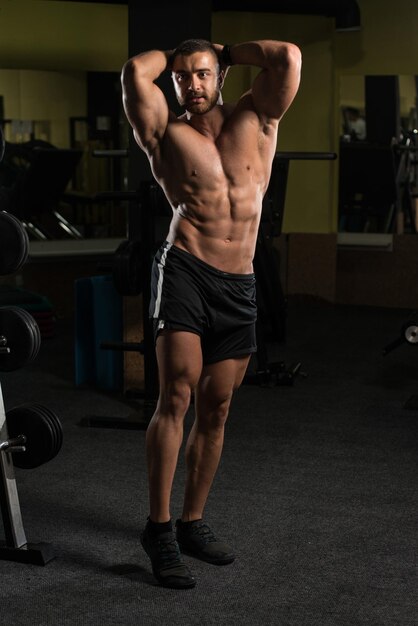 Hombre musculoso flexionando los músculos en el gimnasio