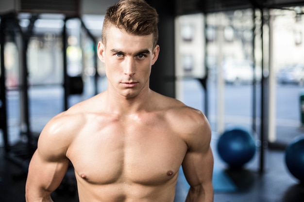 Hombre musculoso en forma posando sin camisa en el gimnasio