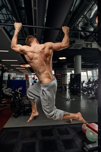 Hombre musculoso fuerte haciendo ejercicio en el gimnasio deportivo Hombre haciendo flexiones horizontales con barras en el gimnasio Gimnasio de fondo con espacio de copia