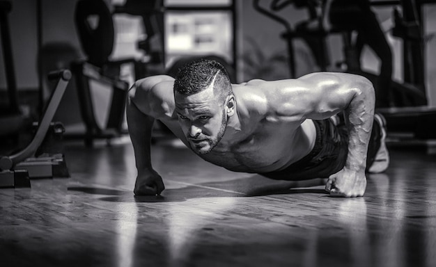 Hombre musculoso y fuerte haciendo ejercicio Hombre delgado haciendo flexiones en el gimnasio Hombre haciendo flexiones Blanco y negro