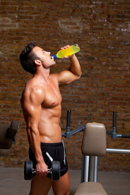 Hombre musculoso en el gimnasio relajado con bebida energética