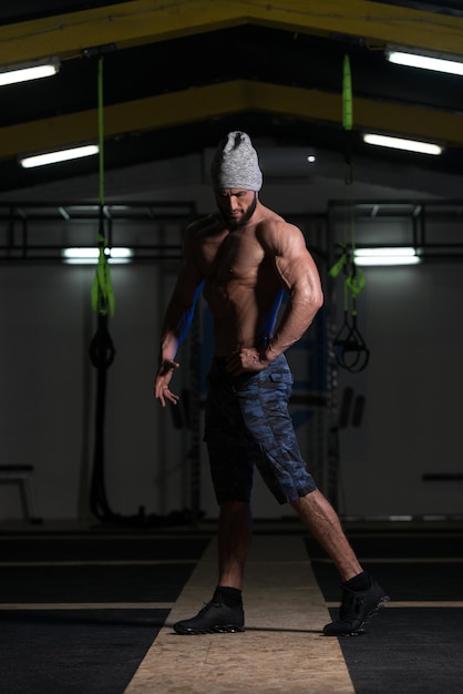 Hombre musculoso guapo flexionando los músculos en el gimnasio