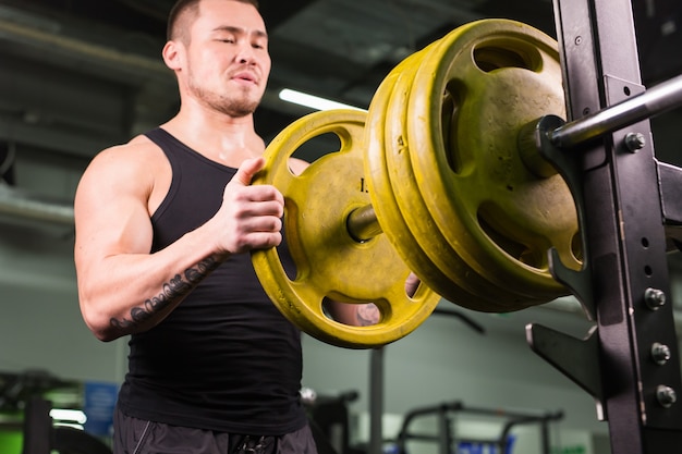 Foto hombre musculoso guapo en gimnasio de cerca