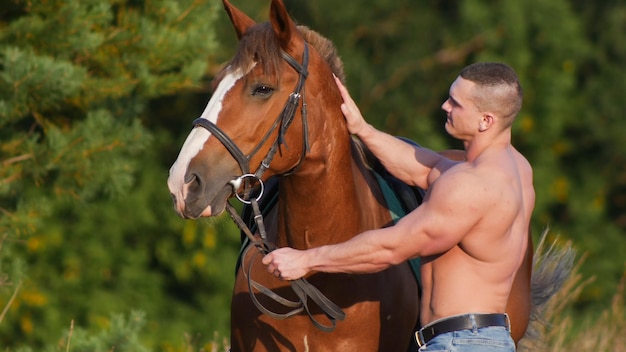 Hombre musculoso guapo montando a caballo en la naturaleza
