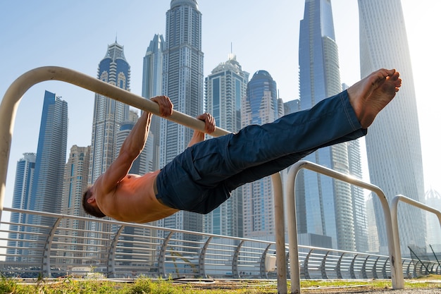 Hombre musculoso haciendo ejercicio en la calle con paisaje urbano de rascacielos en superficie en Dubai