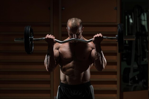 Hombre musculoso haciendo ejercicio pesado para bíceps