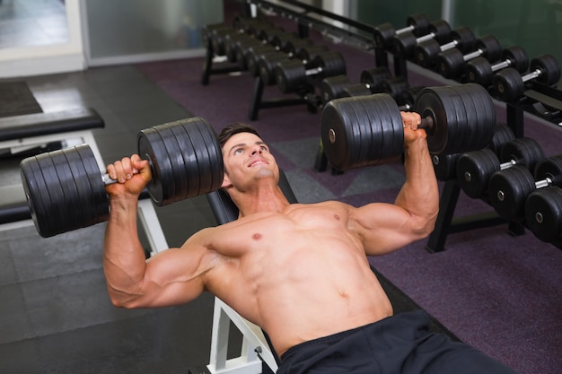 Hombre musculoso haciendo ejercicio con pesas en el gimnasio