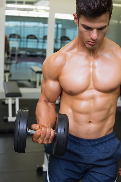 Hombre musculoso haciendo ejercicio con pesas en el gimnasio