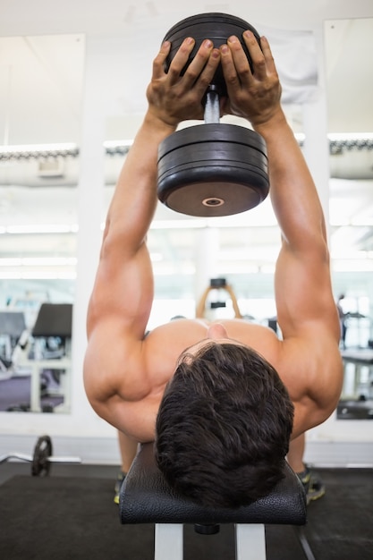 Foto hombre musculoso haciendo ejercicio con pesas en el gimnasio