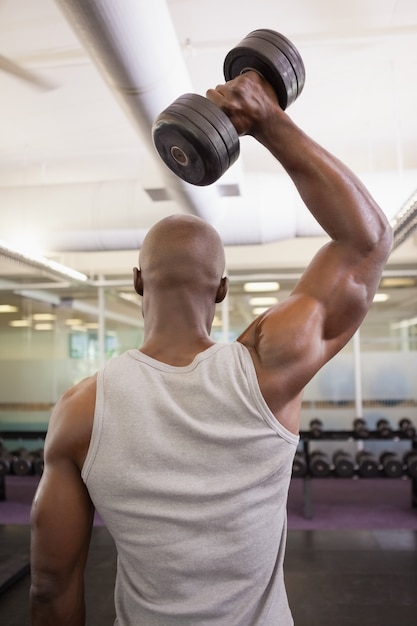 Hombre musculoso haciendo ejercicio con pesas en el gimnasio