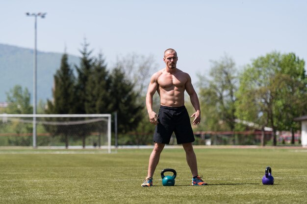 Hombre musculoso haciendo ejercicio con pesas rusas al aire libre