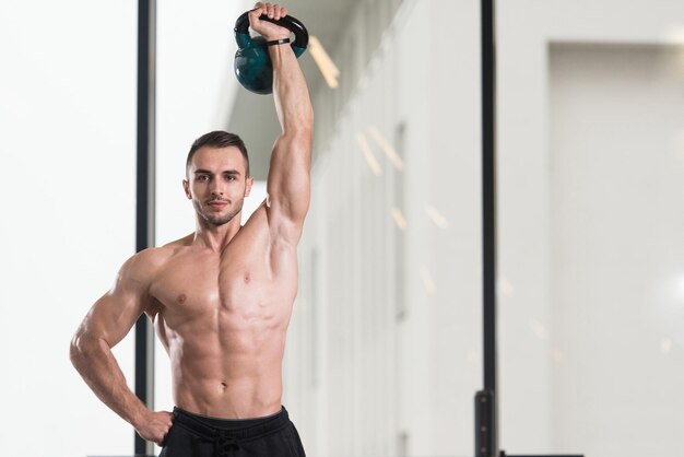 Hombre musculoso haciendo ejercicio con pesas rusas