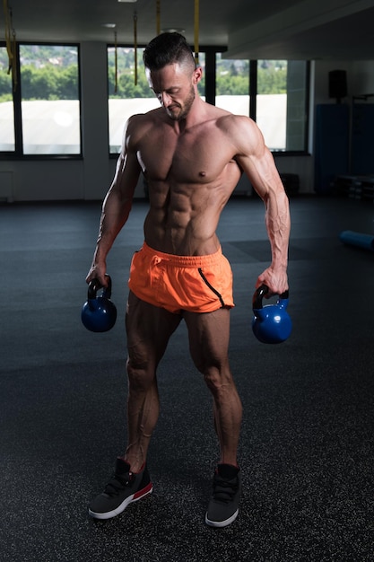 Hombre musculoso haciendo ejercicio con pesas rusas