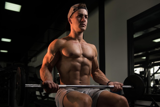 Hombre musculoso haciendo ejercicio de peso pesado para bíceps con pesas en el gimnasio