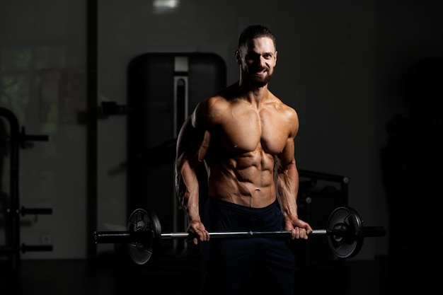 Hombre musculoso haciendo ejercicio de peso pesado para bíceps con pesas en el gimnasio