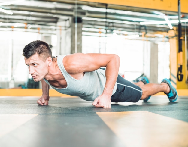 Hombre musculoso haciendo flexiones en el gimnasio