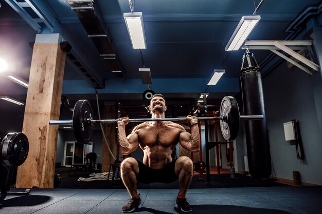 Hombre musculoso haciendo peso muerto una barra en el moderno gimnasio. Entrenamiento funcional.