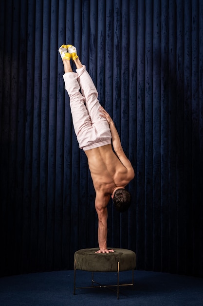 Hombre musculoso haciendo pino por una mano en casa concepto de creatividad de yoga y estilo de vida saludable