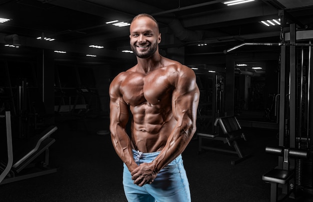 Hombre musculoso en jeans posa en el gimnasio