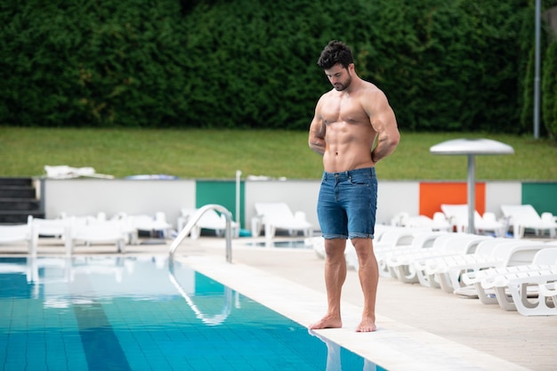 Hombre musculoso joven en la piscina al aire libre