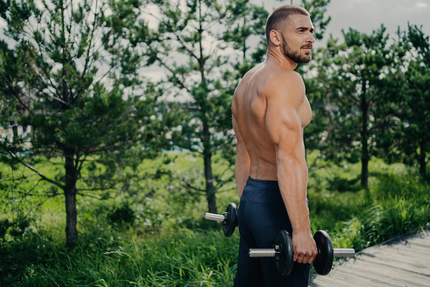 Hombre musculoso levanta pesas motiva al aire libre Inspiración de entrenamiento callejero