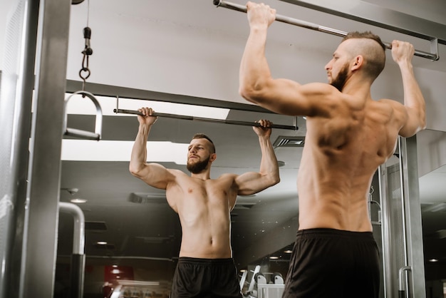 Hombre musculoso levanta su cuerpo en el gimnasio