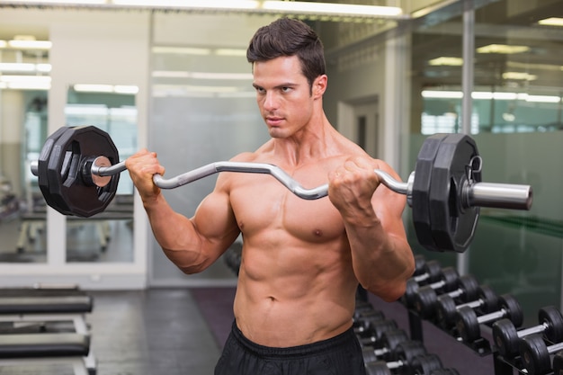 Hombre musculoso levantando barra en el gimnasio