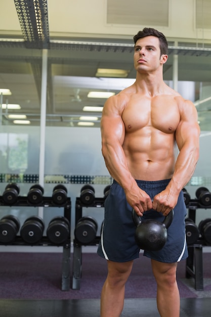 Hombre musculoso levantando la campana de la caldera en el gimnasio