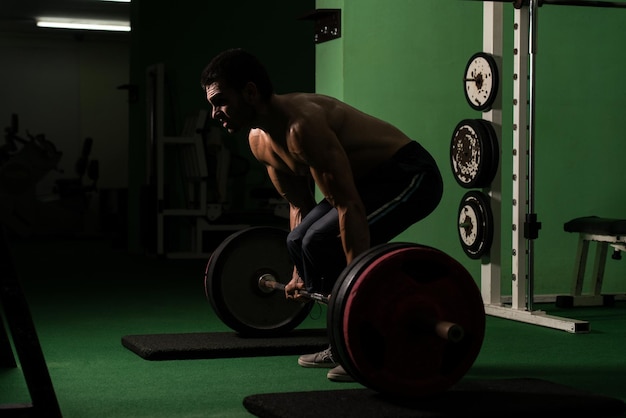 Hombre musculoso levantando peso muerto en el gimnasio