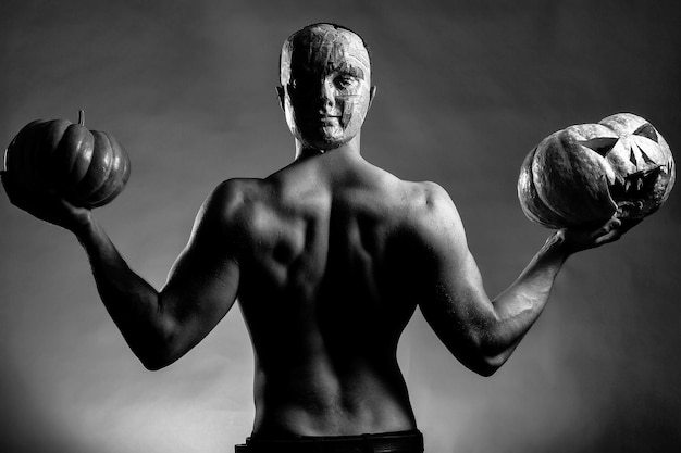 Hombre musculoso en máscara con calabazas