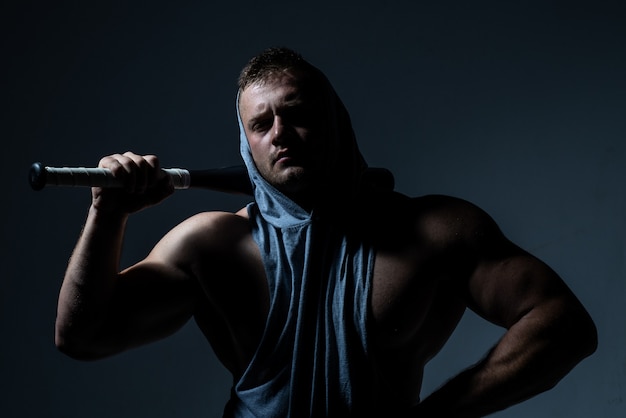 Hombre musculoso peligroso con bate de béisbol listo para pelear.