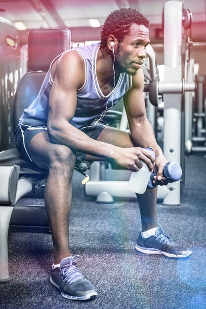 Hombre musculoso pensativo tomando un descanso en el gimnasio