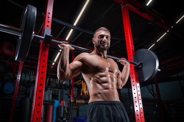 Hombre musculoso posando en el gimnasio con una barra. Concepto de fitness.