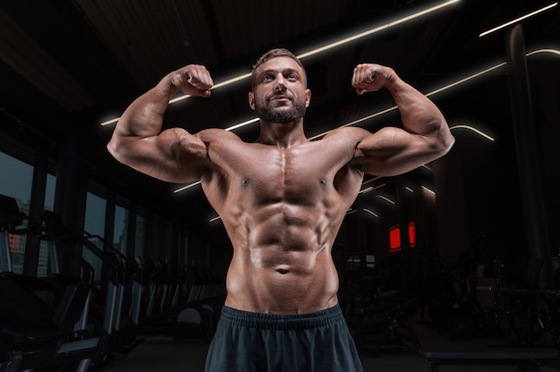 Hombre musculoso posando en el gimnasio con un cinturón atlético. concepto  de fitness.