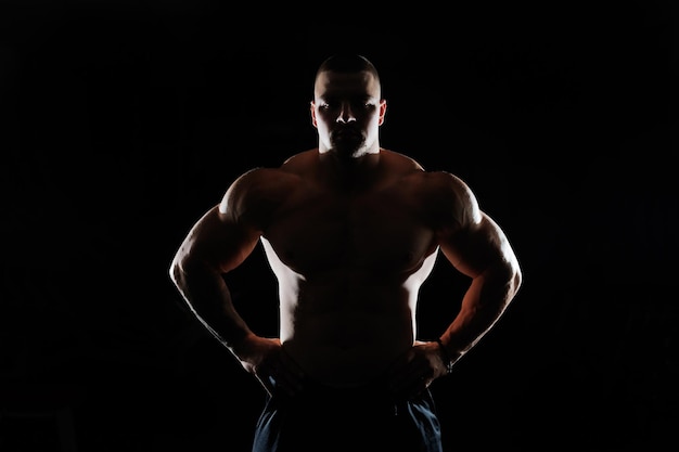 Hombre musculoso que muestra músculos aislados en el fondo negro culturista masculino desnudo torso abdominales