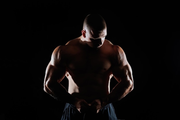 Hombre musculoso que muestra músculos aislados en el fondo negro culturista masculino desnudo torso abdominales