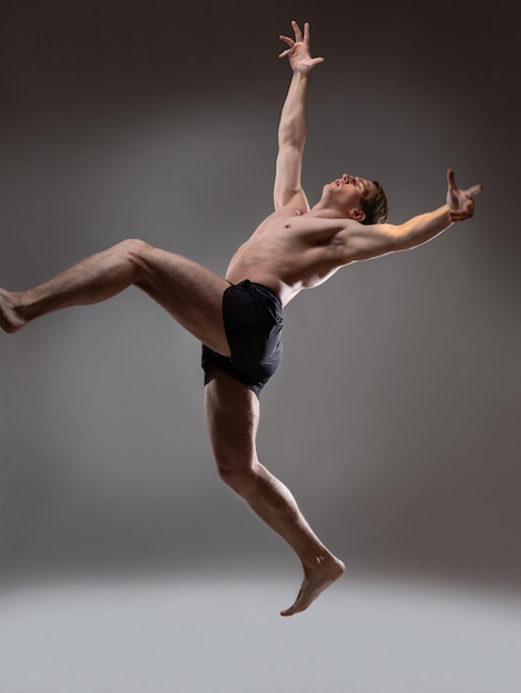 Hombre musculoso en un retrato de pose artística sobre un fondo gris