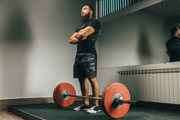 Hombre musculoso en ropa deportiva negra levantando pesas en un gimnasio