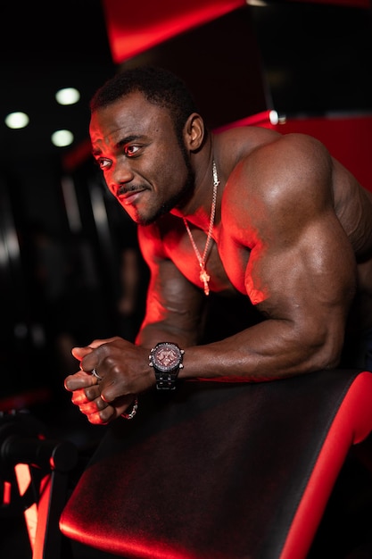 Hombre musculoso de salud con grandes bíceps trabajando en el gimnasio. Culturista guapo deportivo entrenando sus músculos.