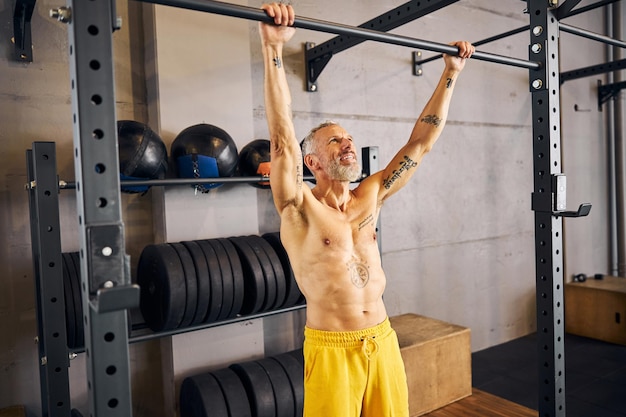 Hombre musculoso sonriente preparándose para hacer dominadas