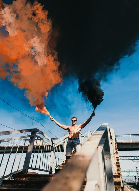 Hombre musculoso sosteniendo bombas de humo en sus manos