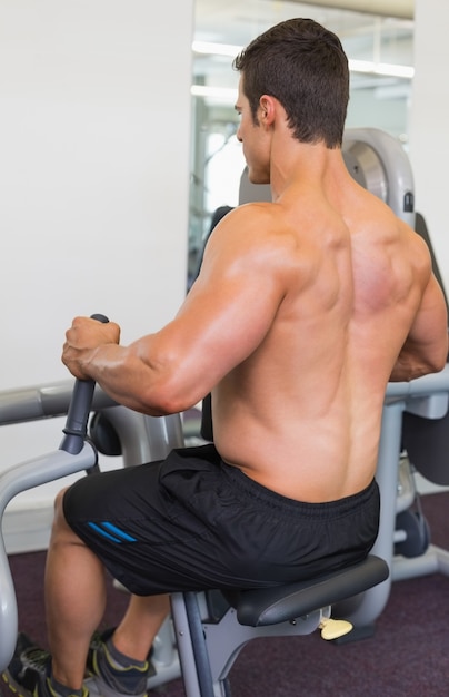 Hombre musculoso trabajando en la máquina abdominal en el gimnasio