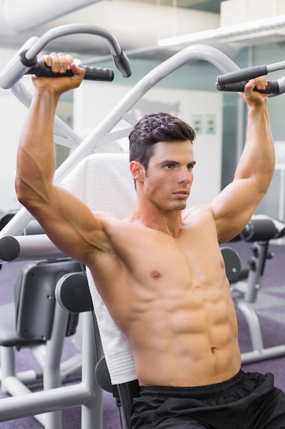 Hombre musculoso trabajando en la máquina de fitness en el gimnasio