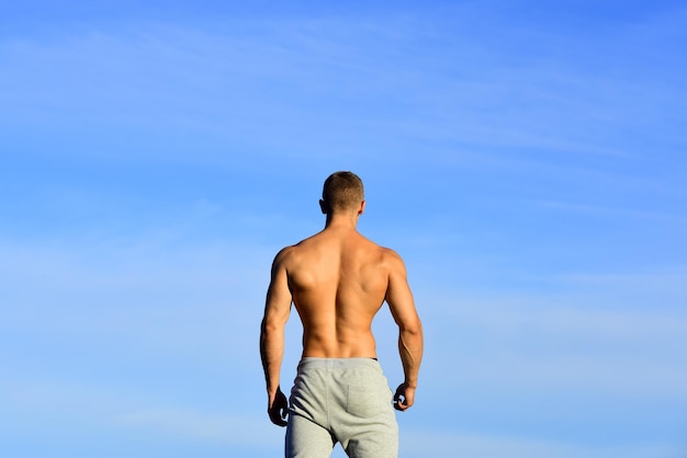 Hombre musculoso de vuelta en el cielo backgraund modelo masculino fuerte