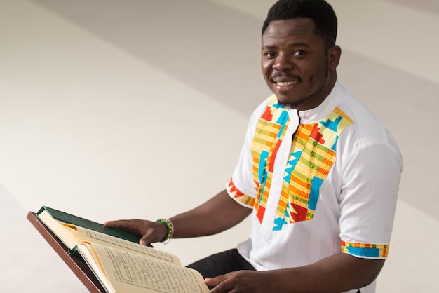 Hombre musulmán africano leyendo el sagrado libro islámico Corán