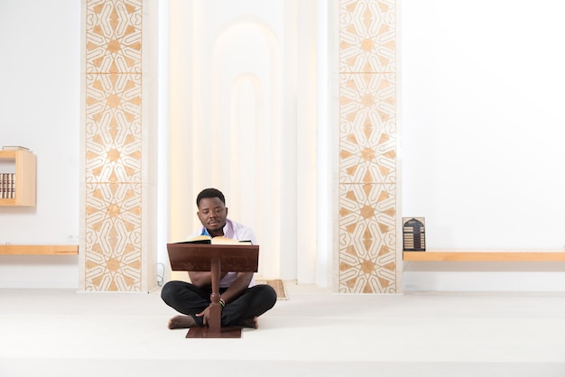 Hombre musulmán africano leyendo el sagrado libro islámico Corán